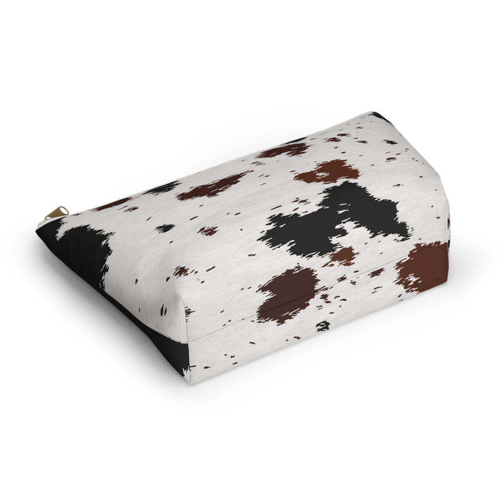 Black and brown cow print cosmetic bag lying at an angle