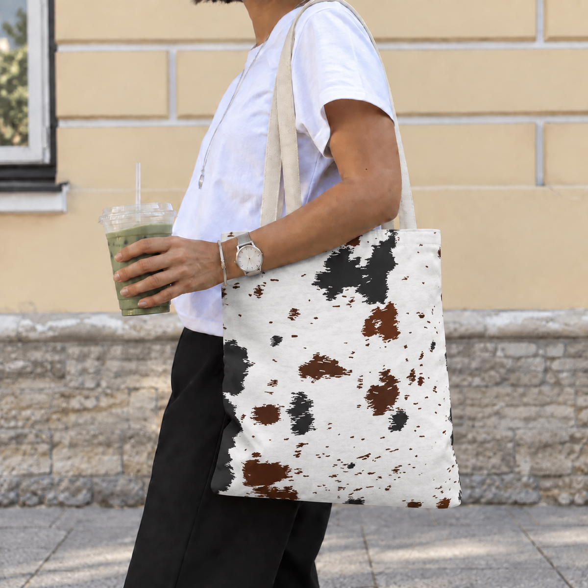 Side view of a woman wearing the black brown cow print tote bag on her shoulder
