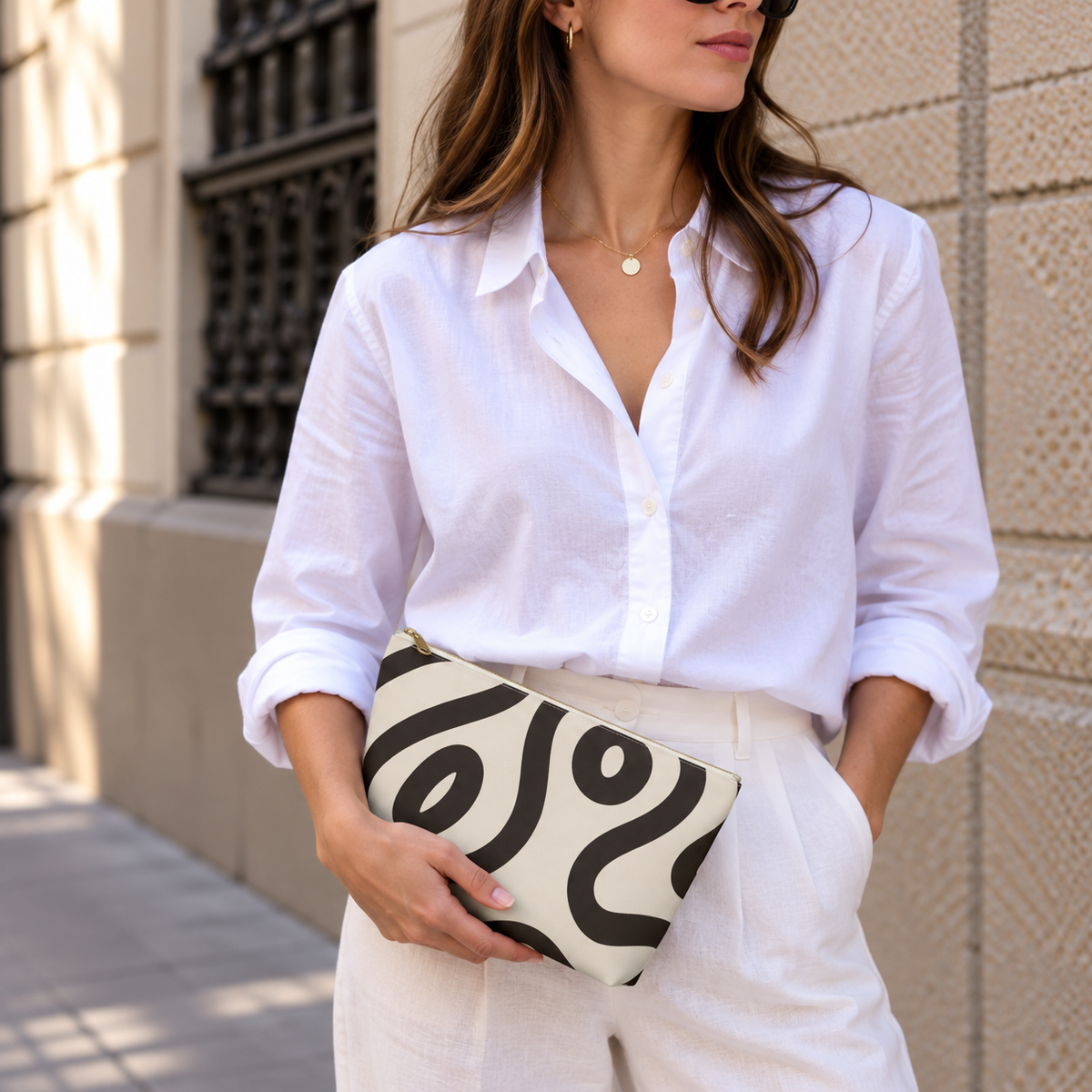 Woman in white shirt holding the black cream abstract makeup bag
