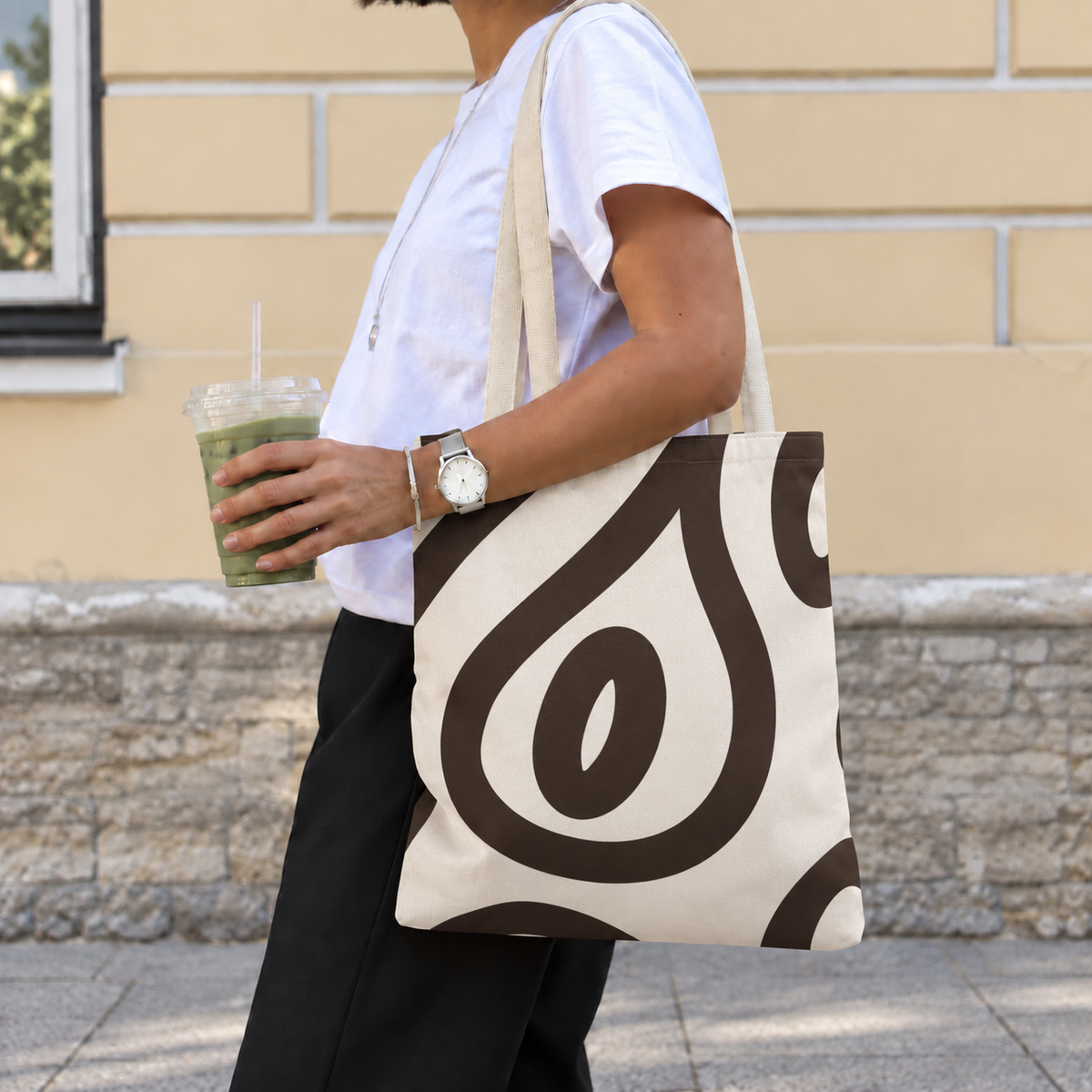 Side view of a person carrying the black cream abstract tote bag on the shoulder