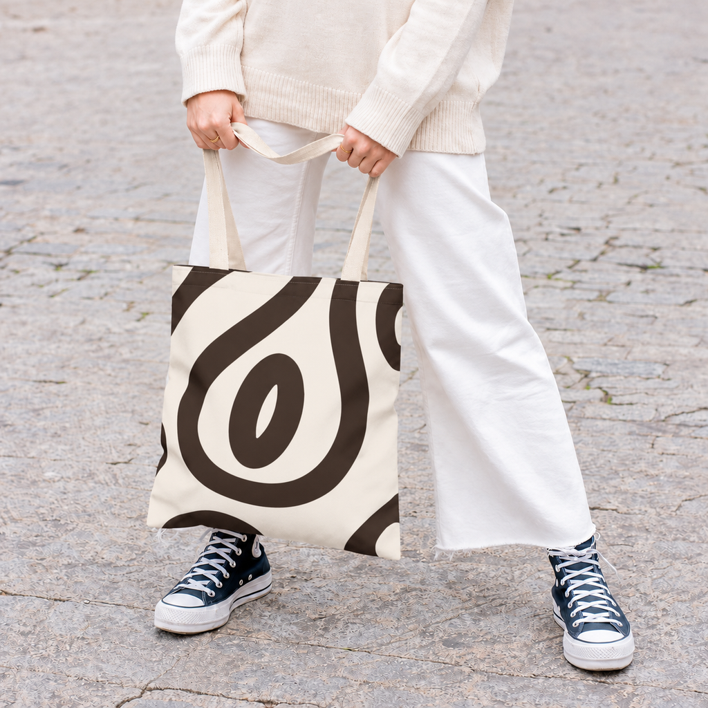 Woman in white trousers holding the black cream abstract tote bag by the handles