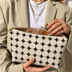 Hands holding the open Black Cream Geometric makeup bag filled with cosmetics