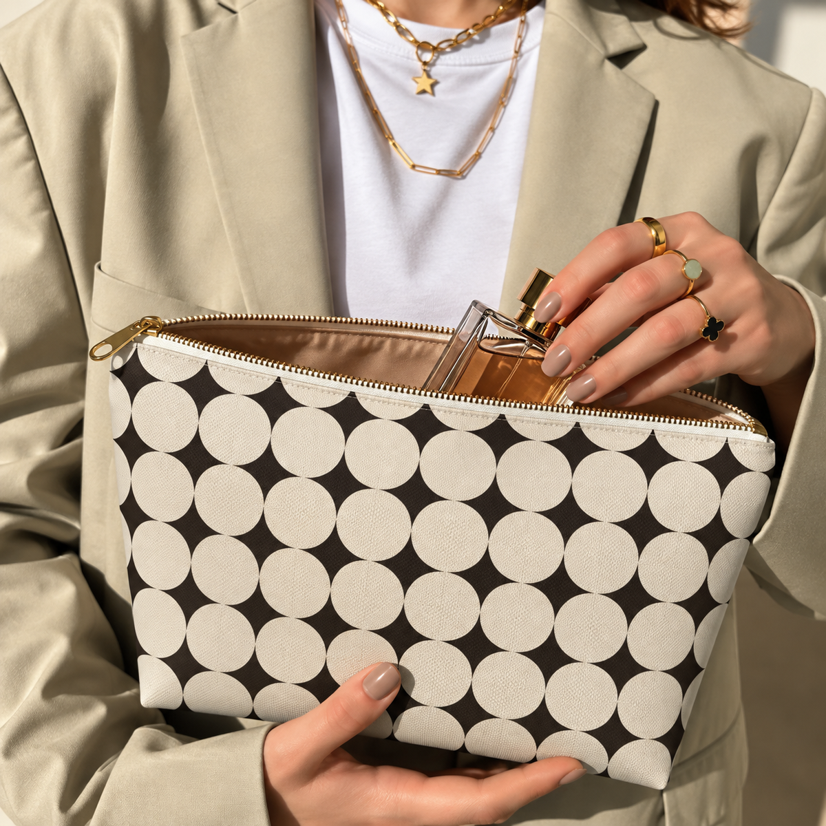 Hands holding the open Black Cream Geometric makeup bag filled with cosmetics