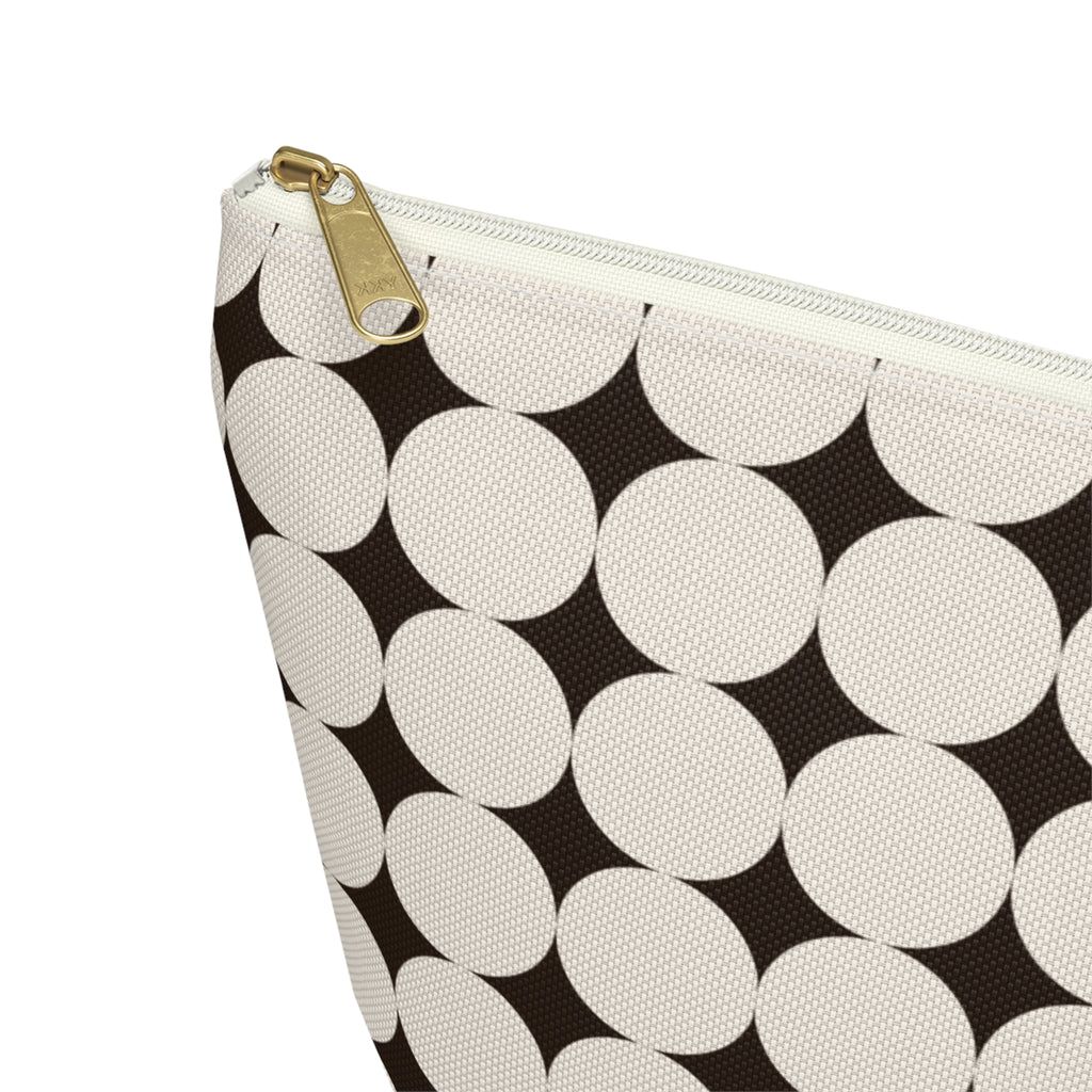 Close-up of the cream circle print on black and gold zipper pull on the makeup bag
