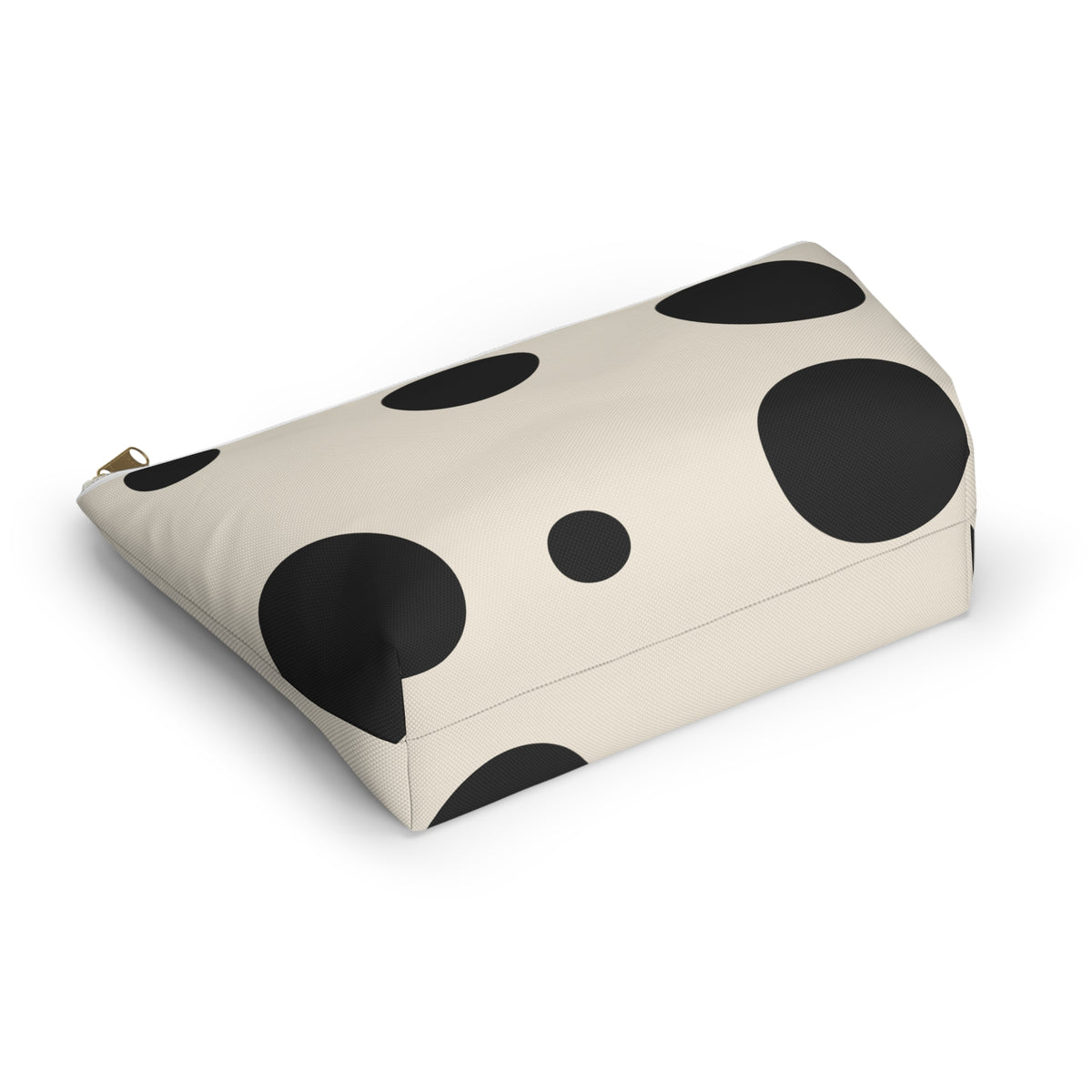 Black and cream polka dot cosmetic bag lying at an angle