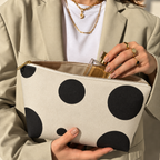 Woman opening the black cream polka dot makeup bag to take out a perfume bottle