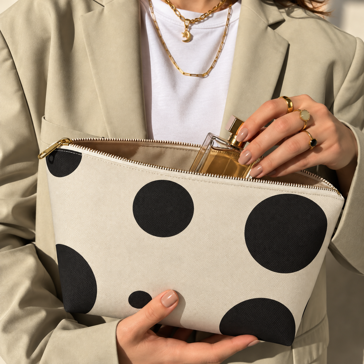 Woman opening the black cream polka dot makeup bag to take out a perfume bottle