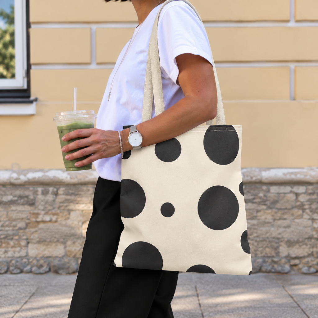 Side view of a woman carrying the black cream polka dot tote bag on her shoulder