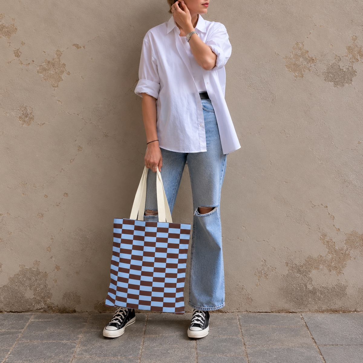 Woman in white shirt and jeans standing with the blue brown brick tote bag