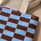 Close-up of the light blue and brown block print and the beige handle of the tote bag