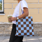 Side view of a person carrying the blue brown checkered tote bag on the shoulder
