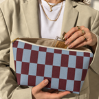 Hands holding the open blue burgundy checkerboard makeup bag