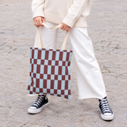 Woman in white trousers holding the blue burgundy checkerboard tote bag by its handles