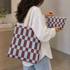 Woman wearing the blue burgundy checkerboard tote bag with the matching makeup bag in her hand