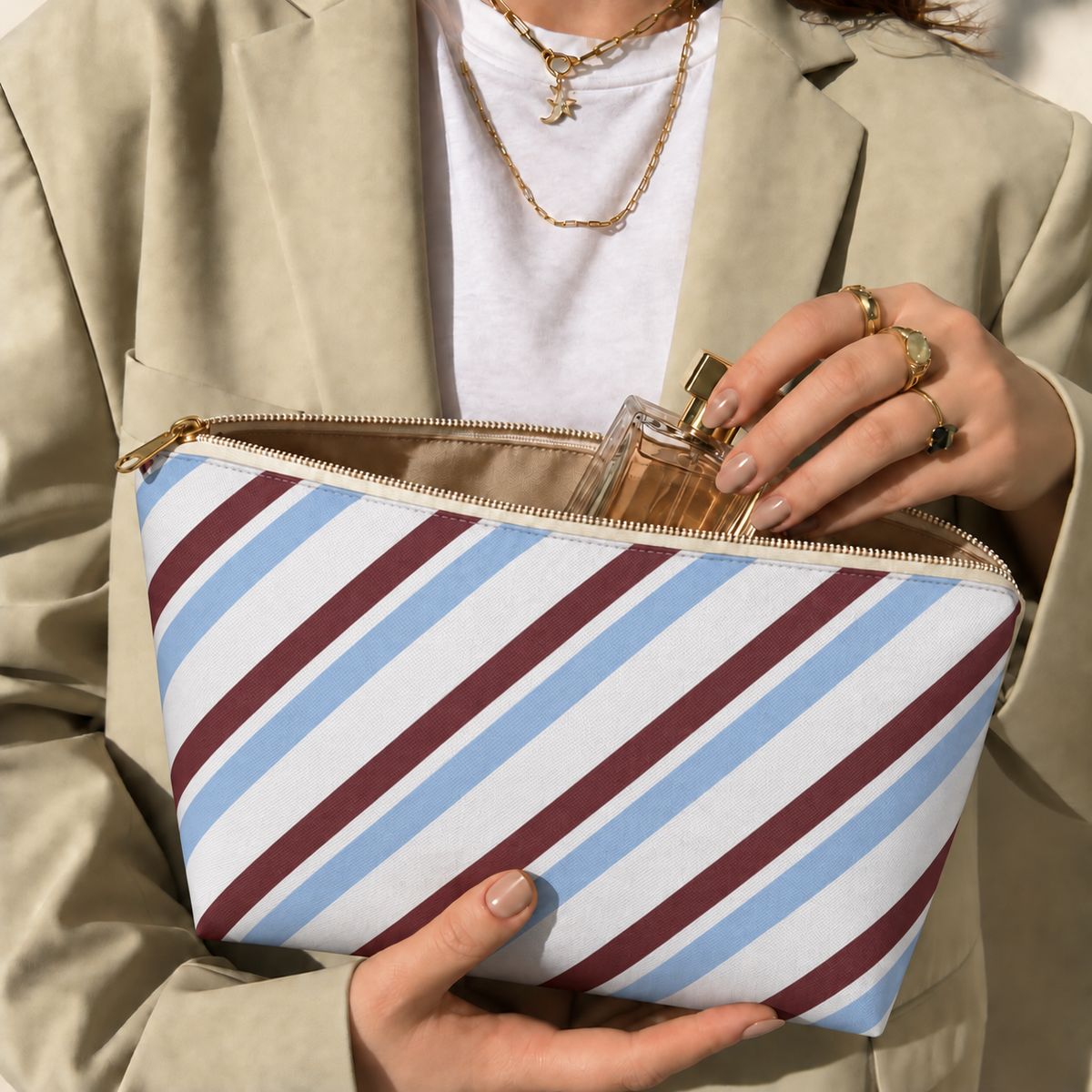Hands holding the open blue burgundy diagonal striped makeup bag