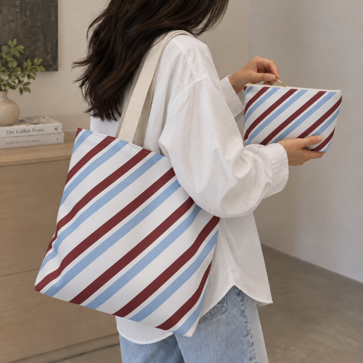 Woman carrying the blue burgundy diagonal striped tote bag with the matching makeup bag in her hand