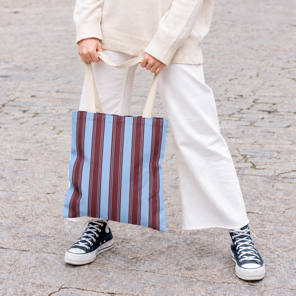 Person in white trousers and sneakers holding the striped tote bag in front of them