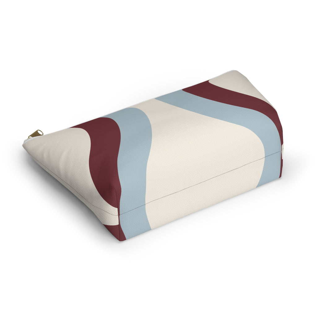 Wavy makeup bag lying on its side showing the blue and burgundy curved print