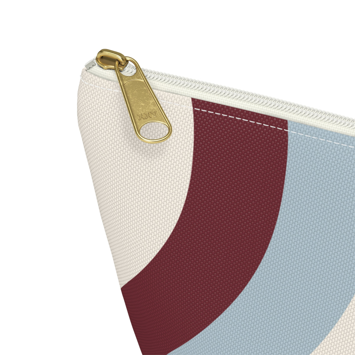 Close-up of the gold zipper pull and wavy burgundy and blue print on the makeup bag