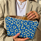 Woman holding the leopard print makeup bag open with a perfume bottle inside