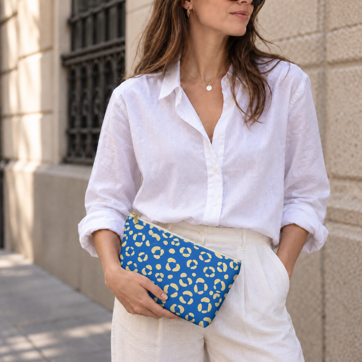 Woman in a white shirt holding the blue leopard print makeup bag as a clutch