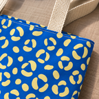 Close-up of the cream leopard spots on cobalt blue fabric and the handle of the tote bag