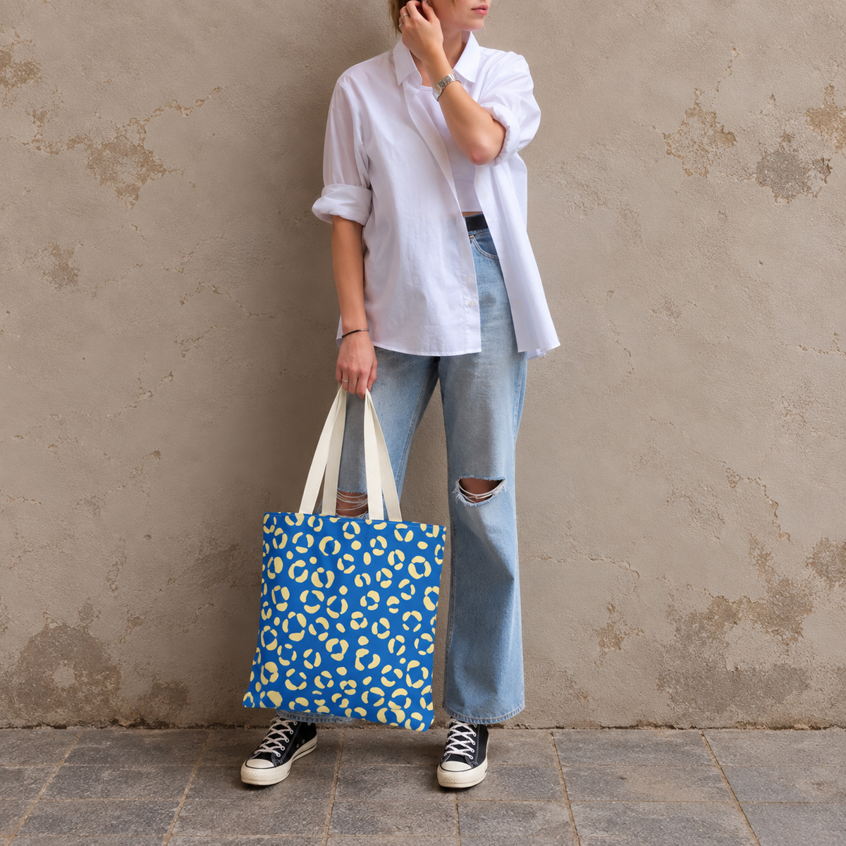 Woman in a white shirt and jeans holding the blue cream leopard print tote bag