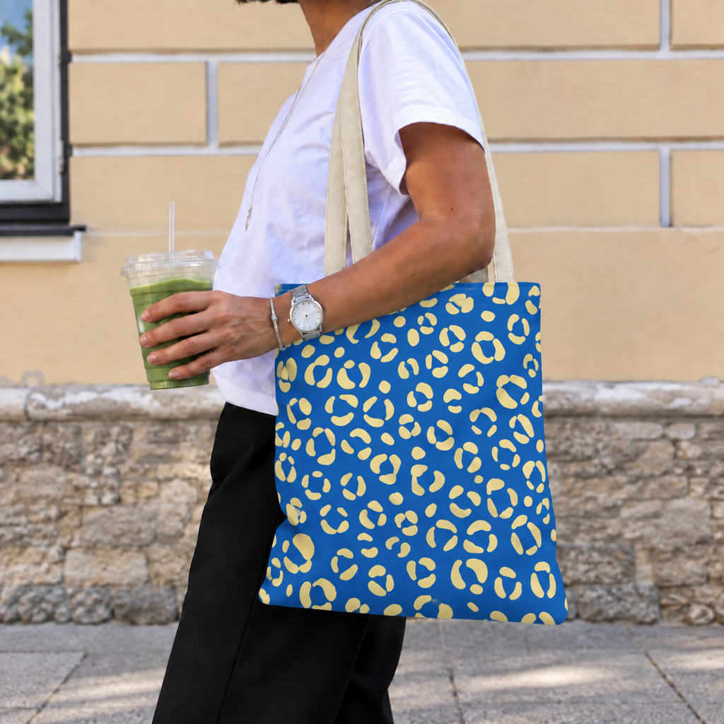 Woman walking with the blue leopard print tote bag on her shoulder and an iced drink