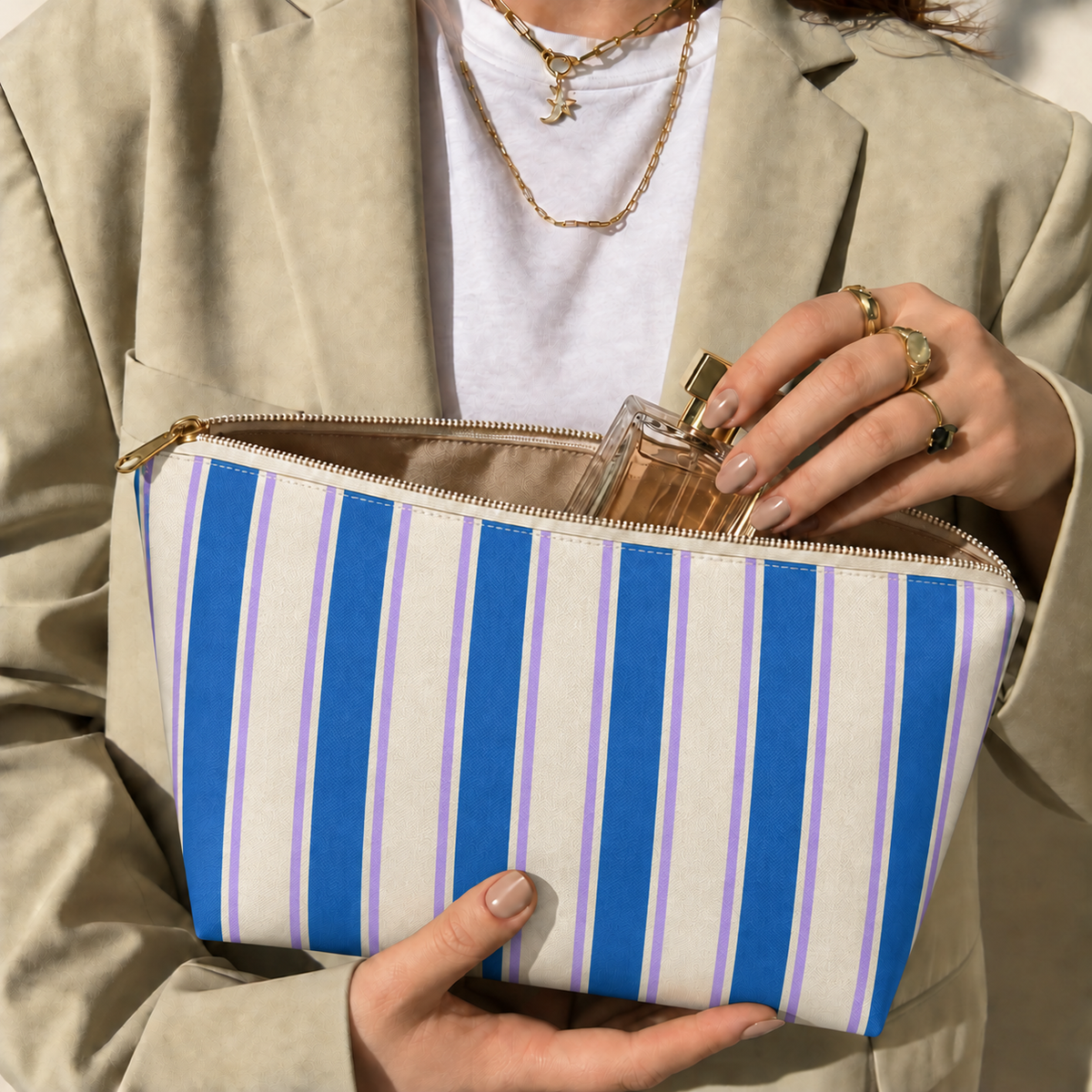 Hands holding the open Blue Cream Striped makeup bag filled with cosmetics