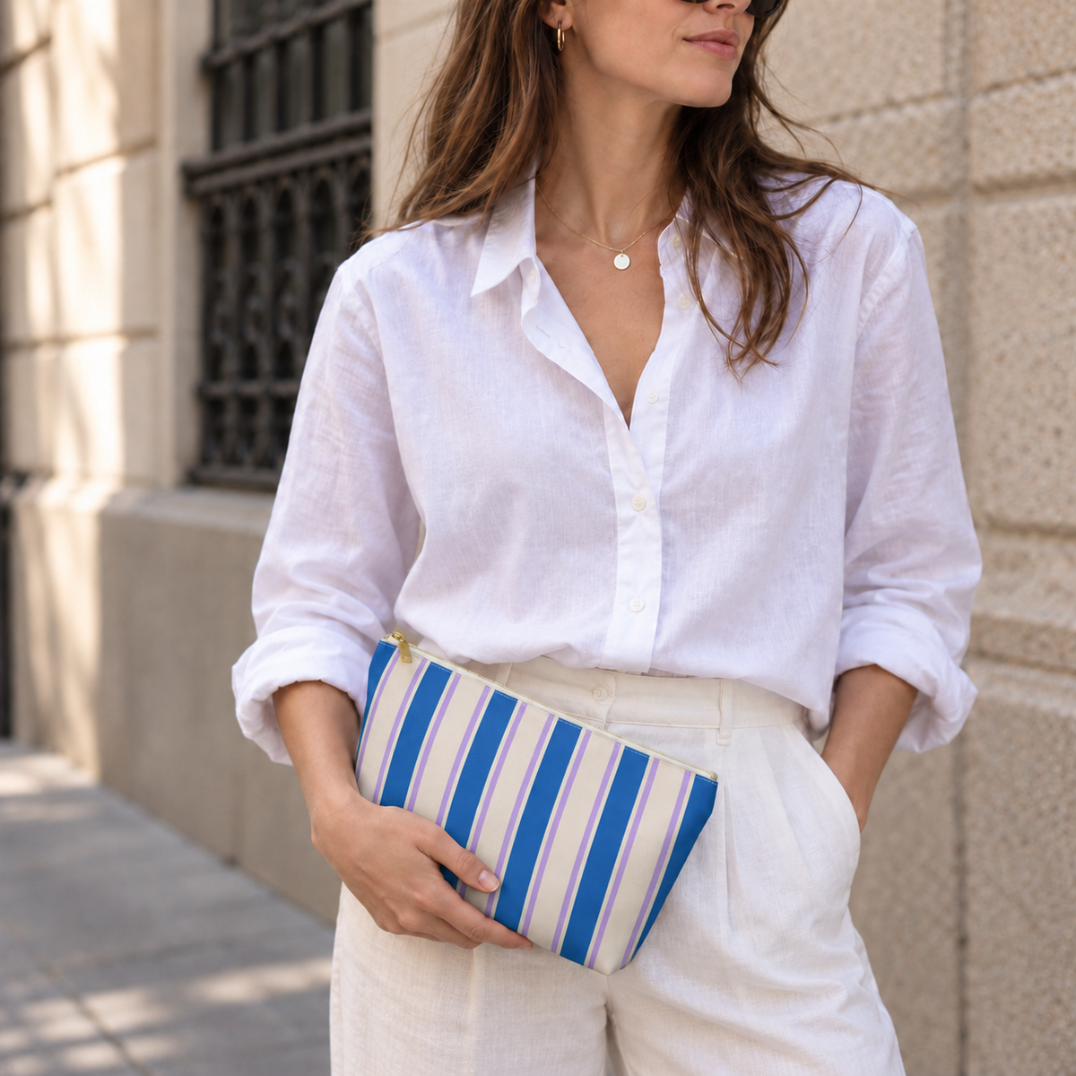 Model holding the Blue Cream Striped makeup bag like a clutch