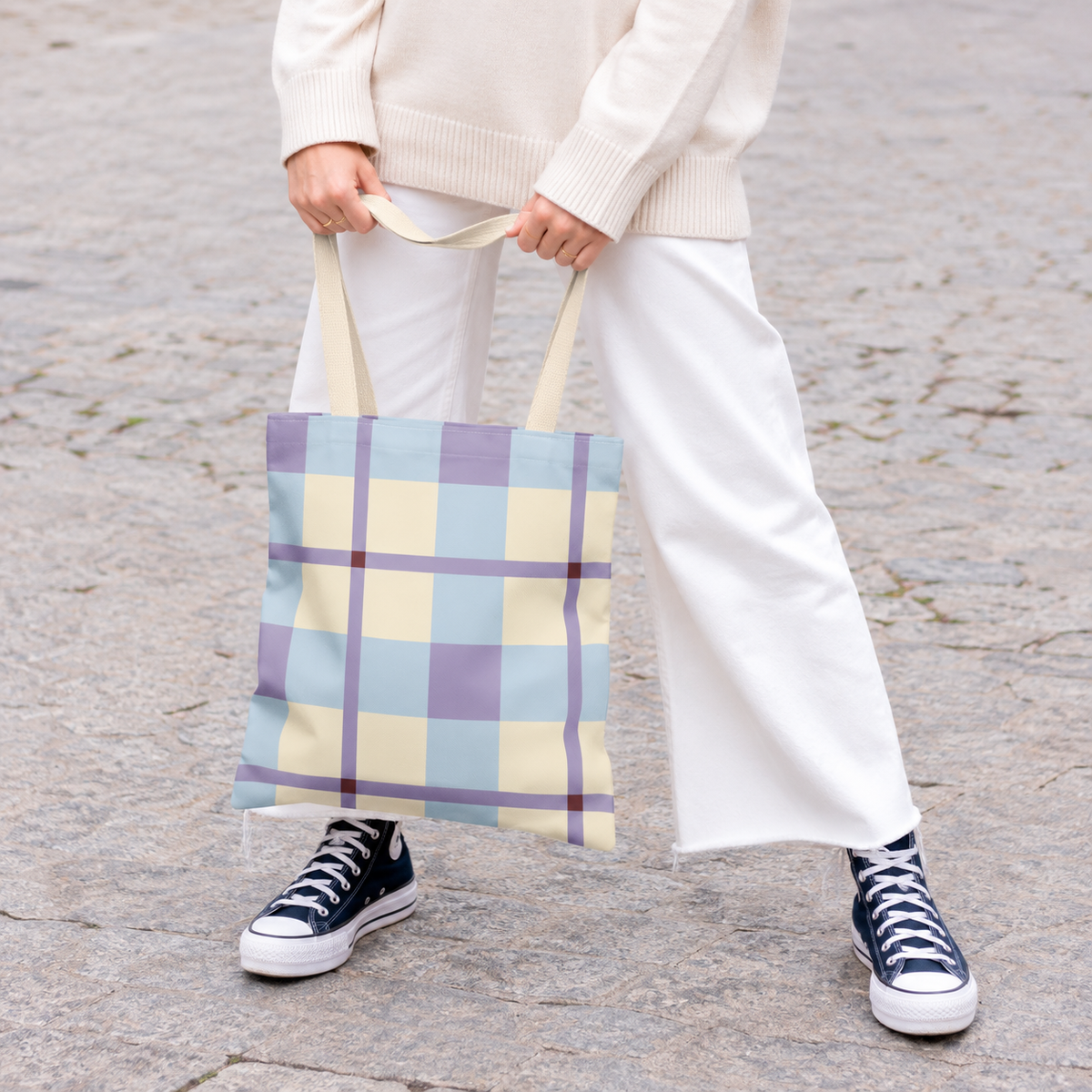 Model holding the blue lilac cream plaid tote bag in front of white trousers