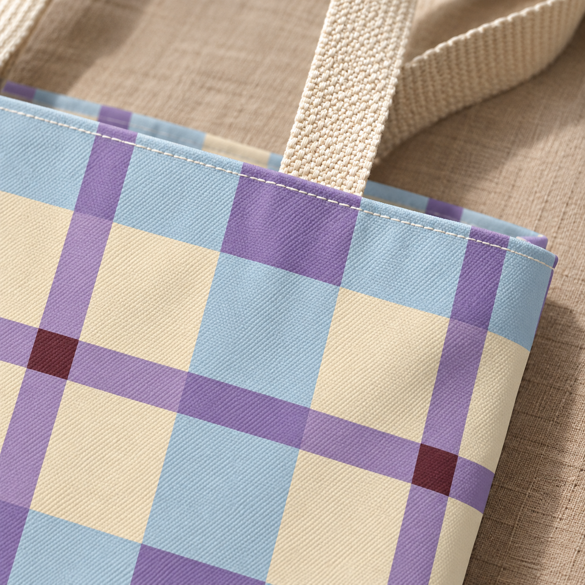 Close-up of the pastel blue, lilac and cream plaid and beige handle on the tote bag