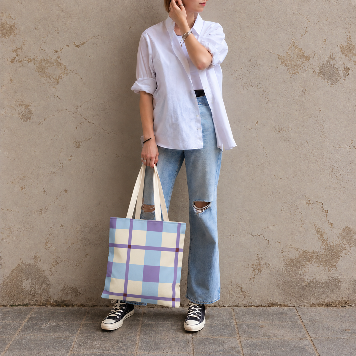 Model in jeans and a white shirt standing with the blue lilac cream plaid tote bag