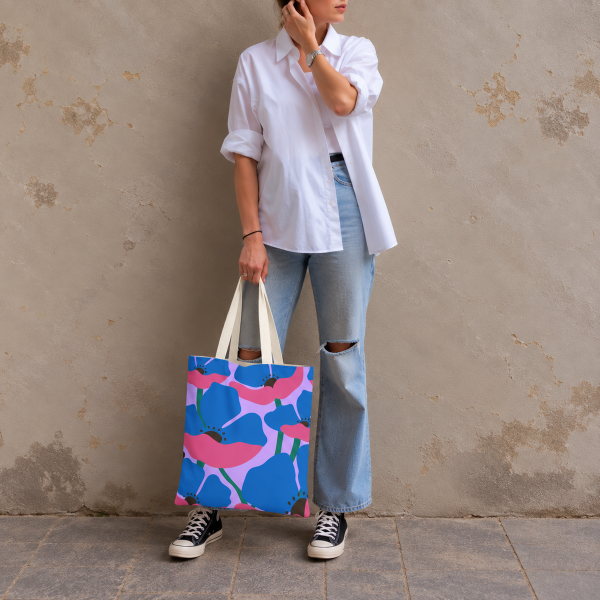 Woman in a white shirt and jeans standing with the blue pink poppy tote bag