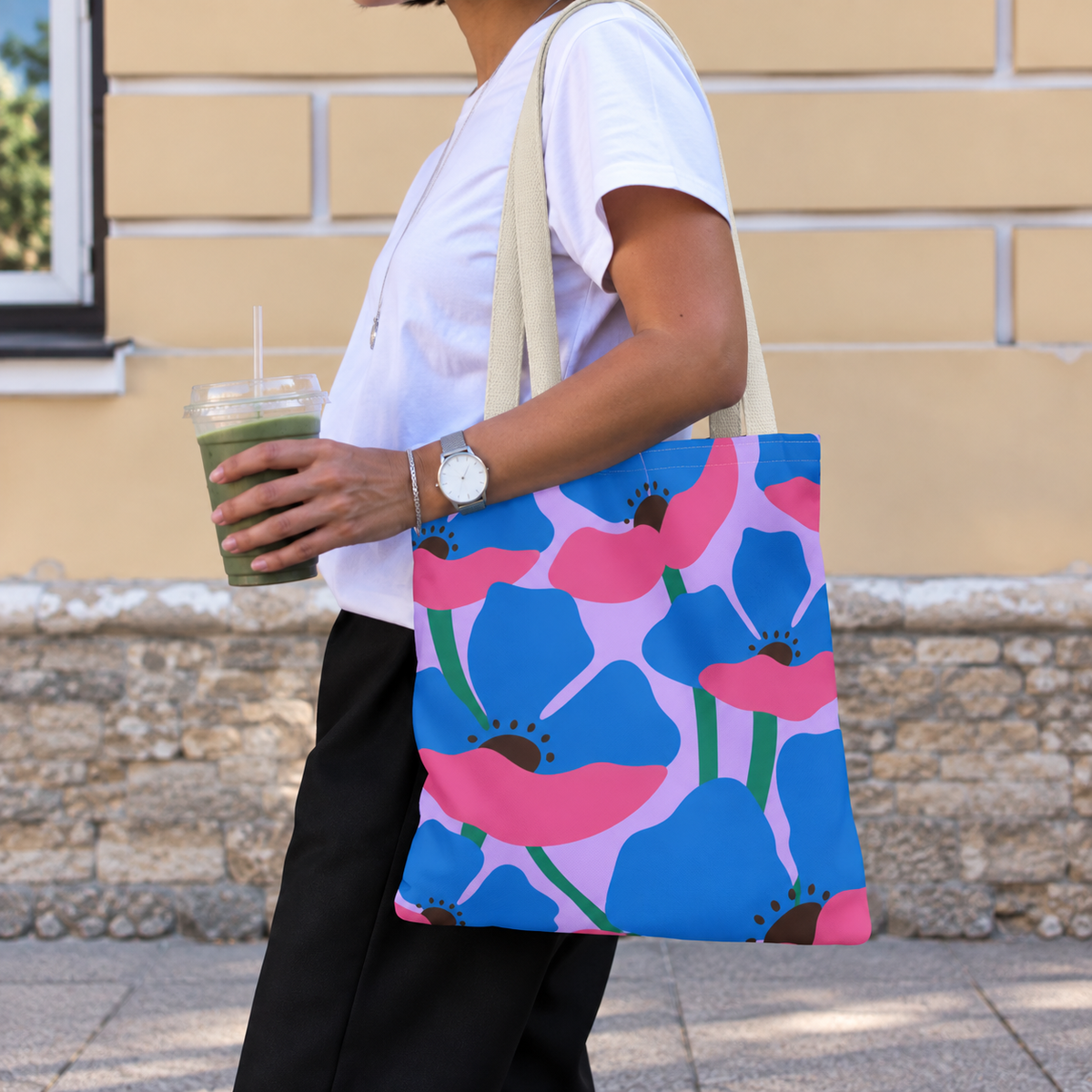 Woman with an iced drink wearing the blue pink poppy floral tote bag on her shoulder
