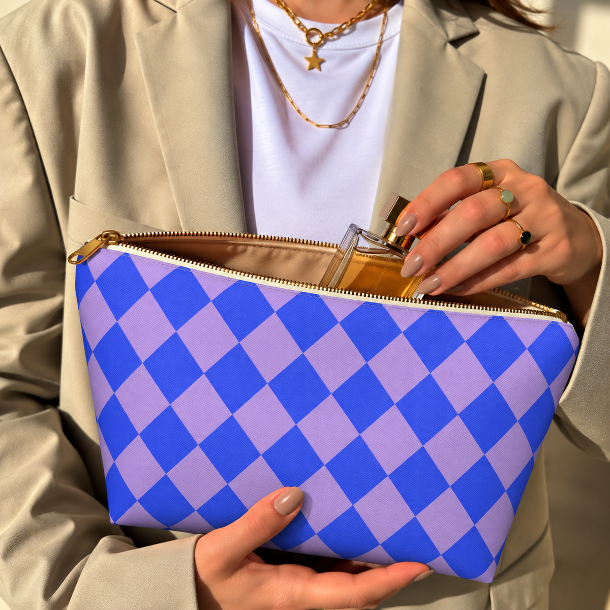 Hands holding the blue purple checkered makeup bag with a perfume bottle inside