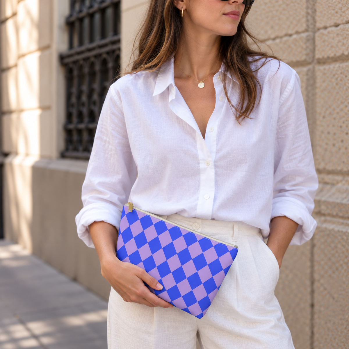 Woman in white shirt holding the blue purple checkered makeup bag as a clutch