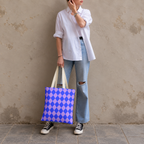 Woman in jeans and sneakers holding the blue purple diamond checkered tote bag