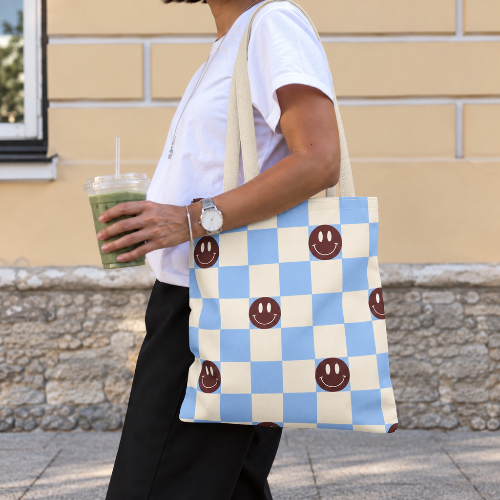 Side view of a woman wearing the blue and cream checkered smiley face tote bag on her shoulder