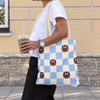 Side view of a woman wearing the blue and cream checkered smiley face tote bag on her shoulder