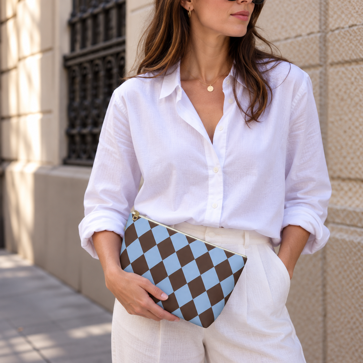 Woman in a white blouse holding a brown blue diamond checkered makeup bag