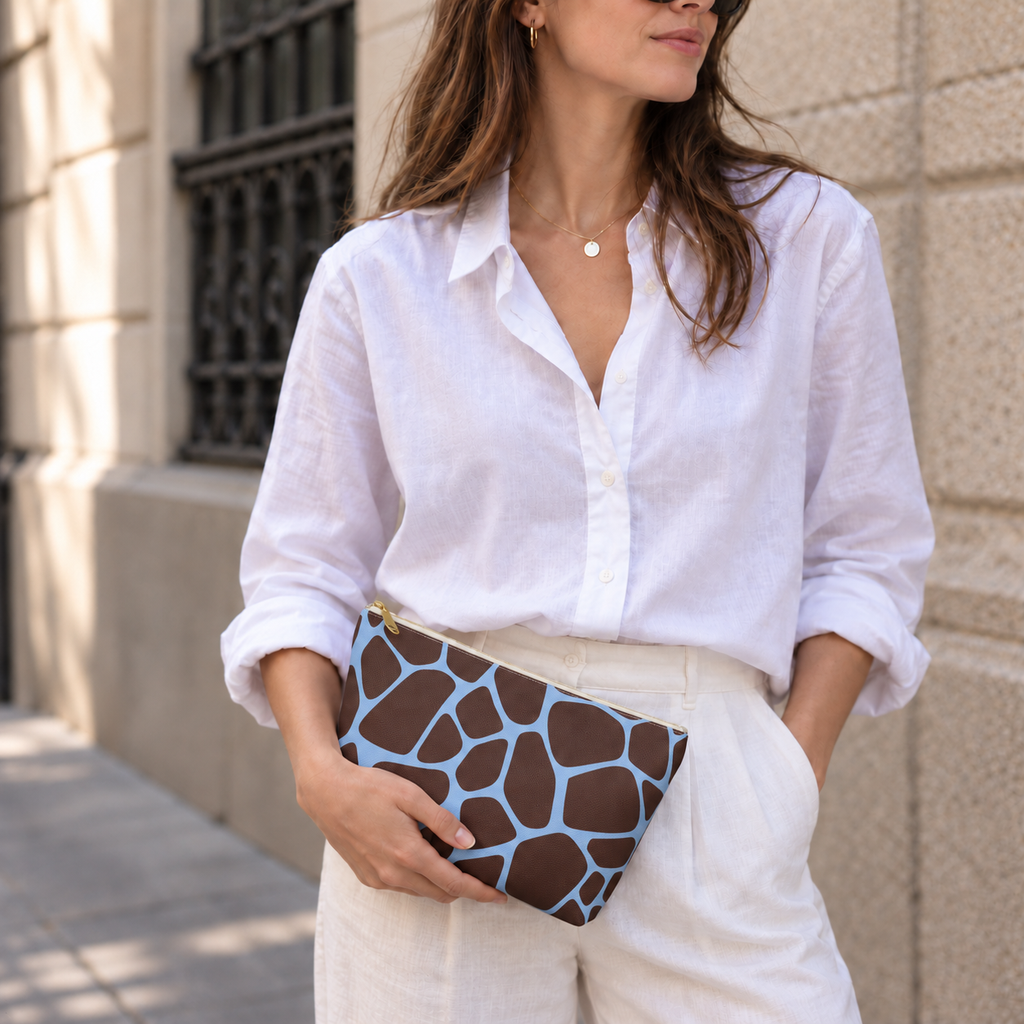 Woman holding a brown blue giraffe print makeup bag like a clutch