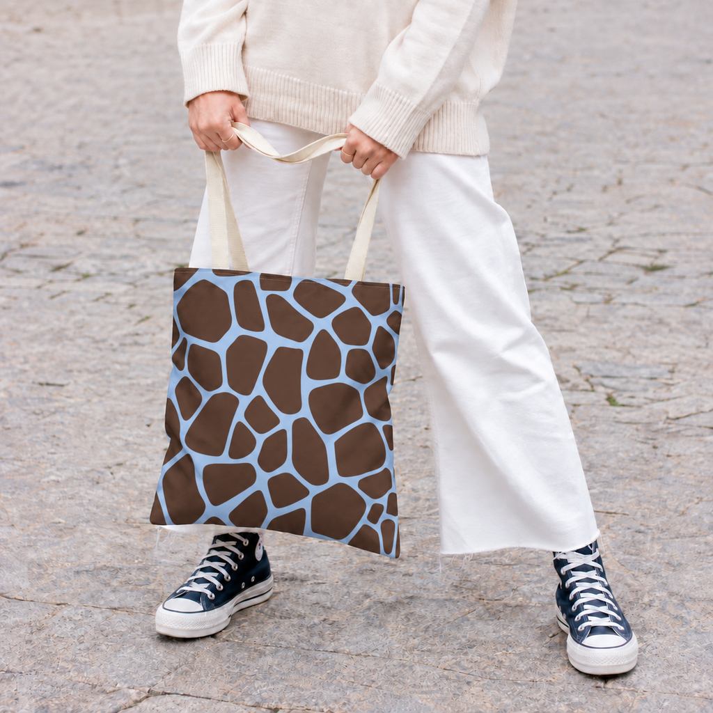 Woman standing with a brown blue giraffe print tote bag, white trousers and sneakers
