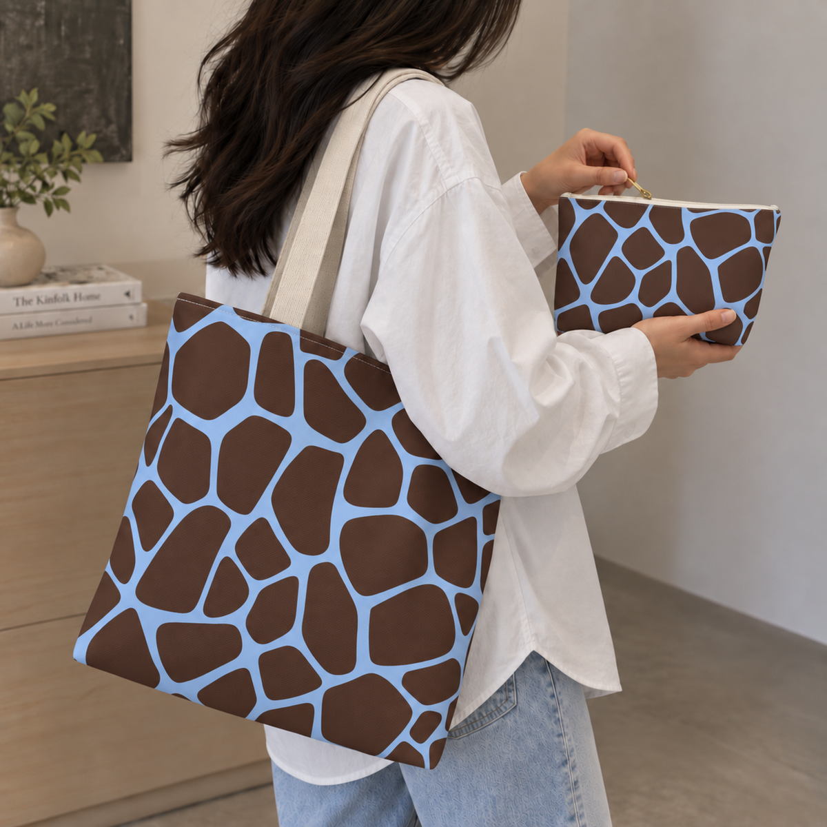 Giraffe print tote bag in brown and blue worn on the shoulder with the matching makeup bag
