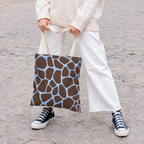 Woman holding a brown blue giraffe print tote bag with white trousers and sneakers