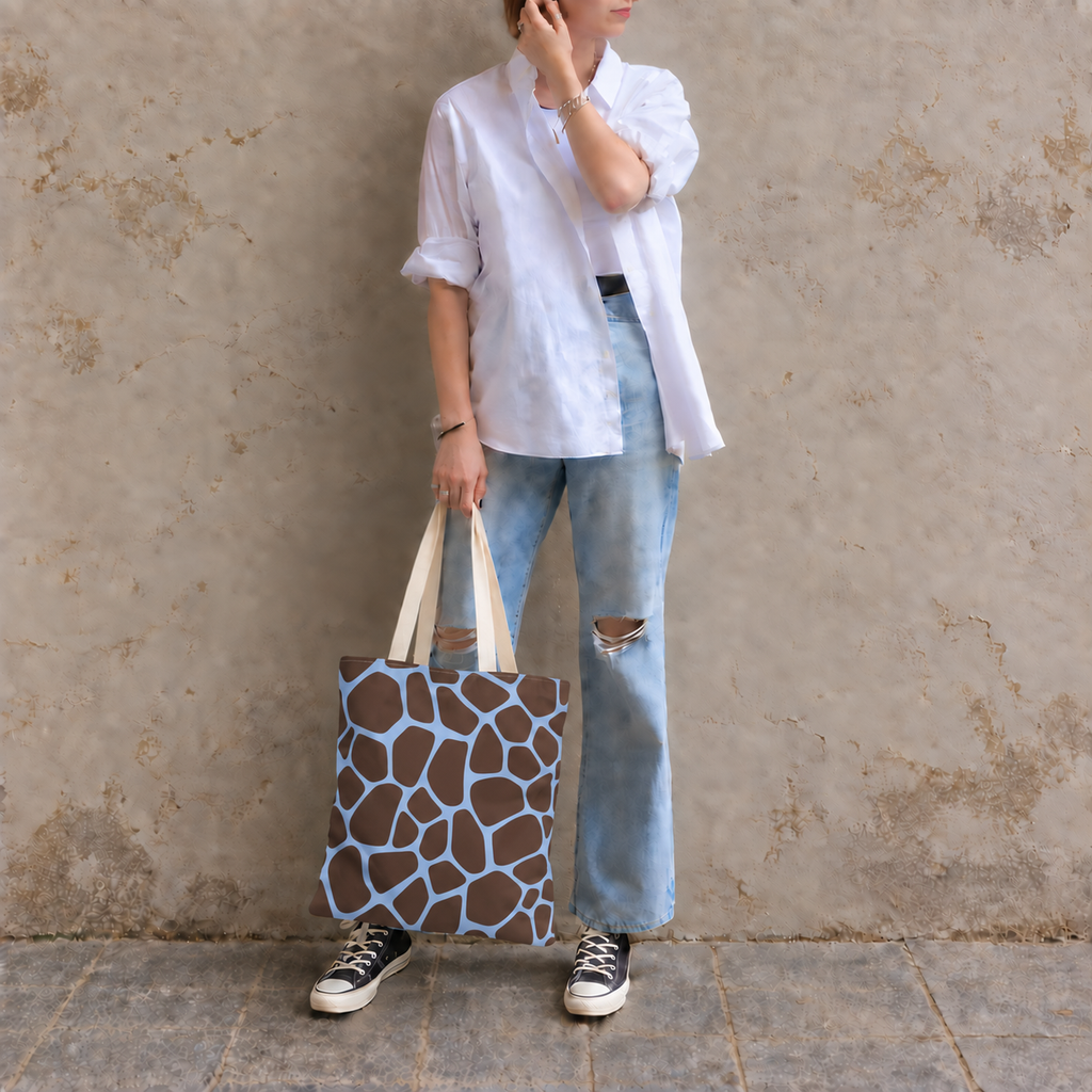 Woman leaning on a wall with a brown blue giraffe print tote bag