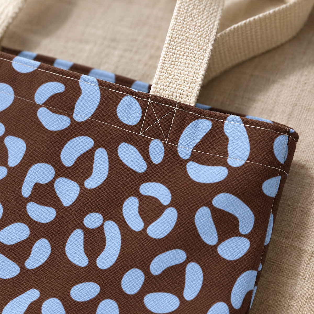 Close-up of the blue leopard spots on brown fabric and the cream tote bag handle