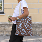 Woman walking with a leopard print tote bag in brown and blue over her shoulder