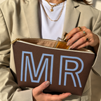 Hands holding the open brown MR personalized makeup bag