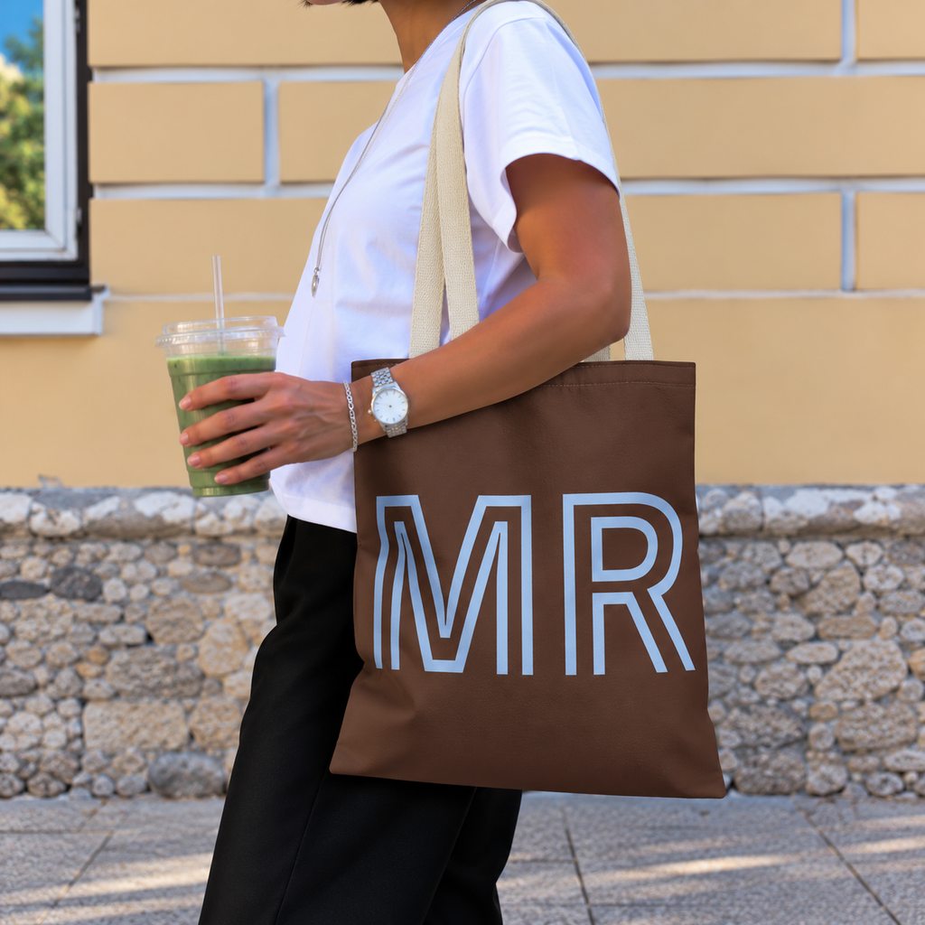 Woman with an iced drink carrying the brown blue monogram personalized tote bag